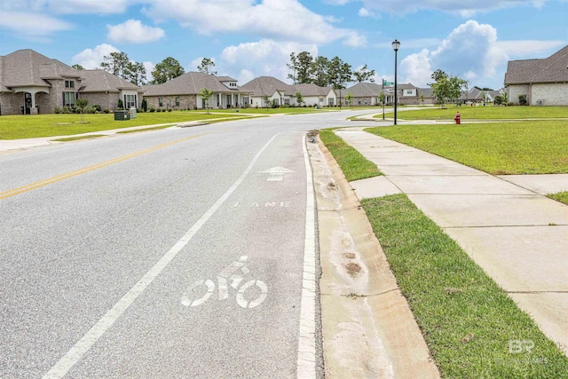 394 Haise Ln, Gulf Shores, AL 36542 - view of asphalt road featuring a residential view, sidewalks, curbs, and street lights