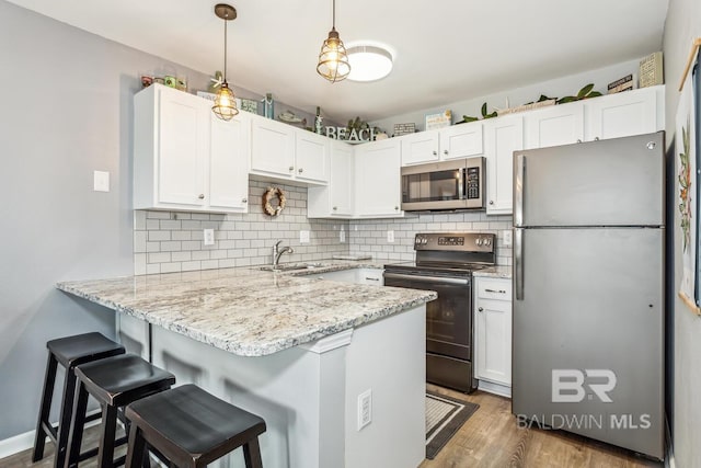 kitchen with dark hardwood / wood-style floors, kitchen peninsula, appliances with stainless steel finishes, and white cabinetry