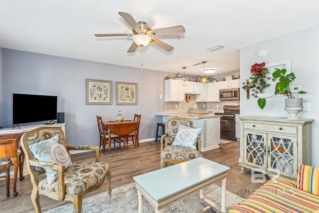 living room with ceiling fan, light wood-type flooring, and sink