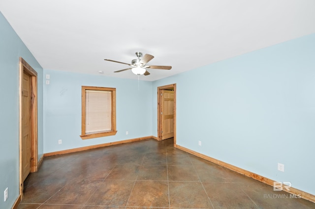 spare room featuring baseboards, dark tile patterned flooring, and ceiling fan