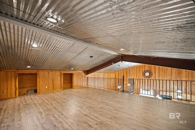 bonus room with lofted ceiling with beams, visible vents, wooden walls, and wood finished floors