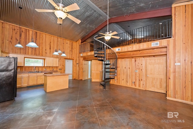 kitchen with high vaulted ceiling, freestanding refrigerator, ceiling fan, a sink, and wood walls
