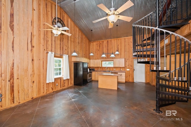 kitchen with stainless steel microwave, wooden walls, freestanding refrigerator, and a sink