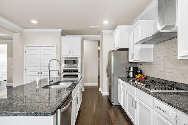 kitchen featuring a sink, wall chimney exhaust hood, stainless steel appliances, white cabinetry, and backsplash