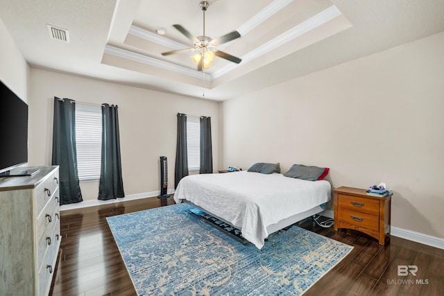 bedroom featuring baseboards, ornamental molding, a tray ceiling, and multiple windows