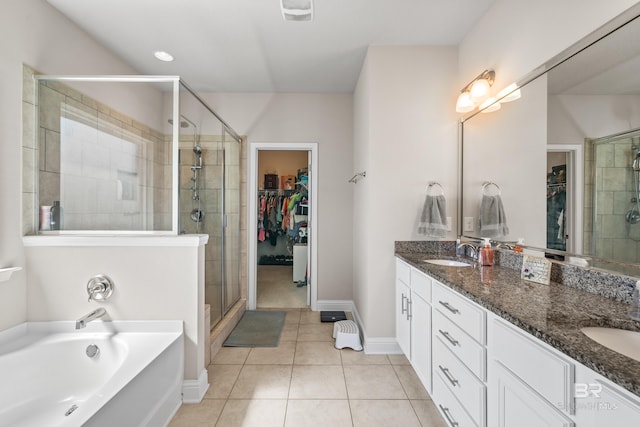 bathroom with double vanity, a stall shower, tile patterned floors, and a spacious closet