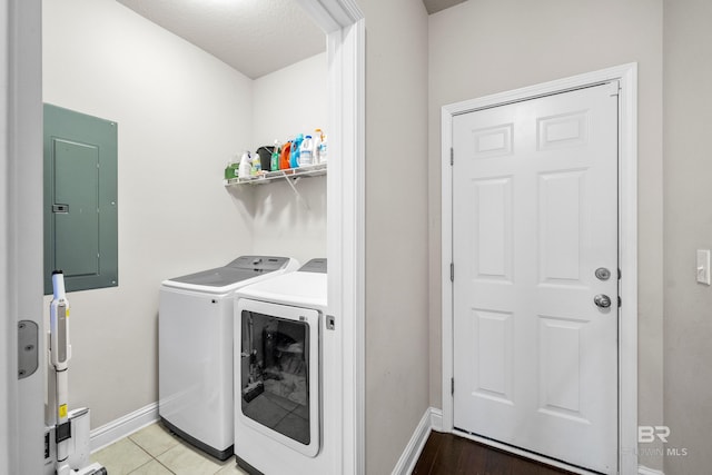 laundry room featuring laundry area, washing machine and dryer, baseboards, and electric panel