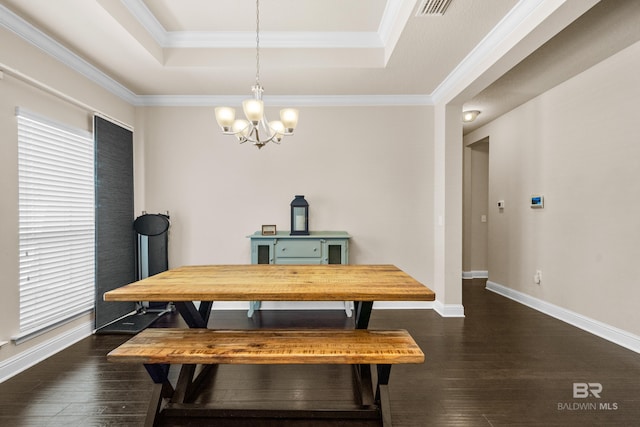 dining area with an inviting chandelier, a raised ceiling, dark wood finished floors, and ornamental molding
