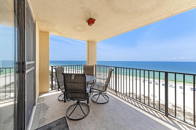 balcony with a water view and a view of the beach