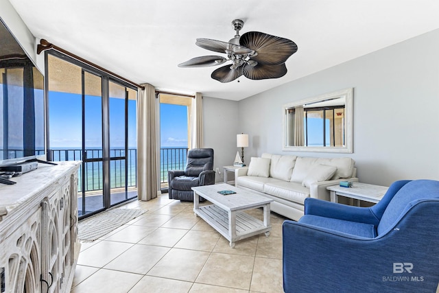 tiled living room with a water view, a wall of windows, and ceiling fan