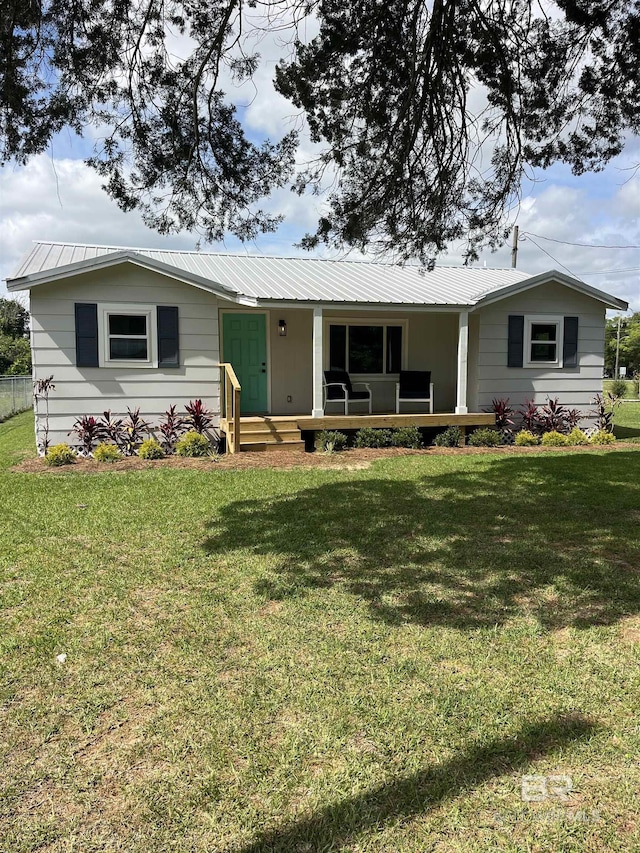 ranch-style house featuring a front lawn, a porch, and metal roof