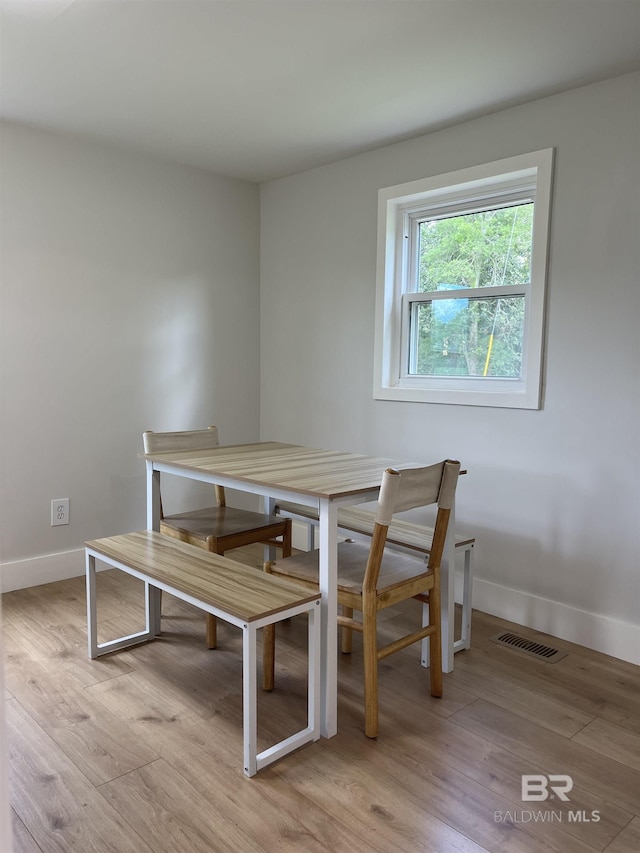 dining room featuring baseboards, visible vents, and light wood-style floors