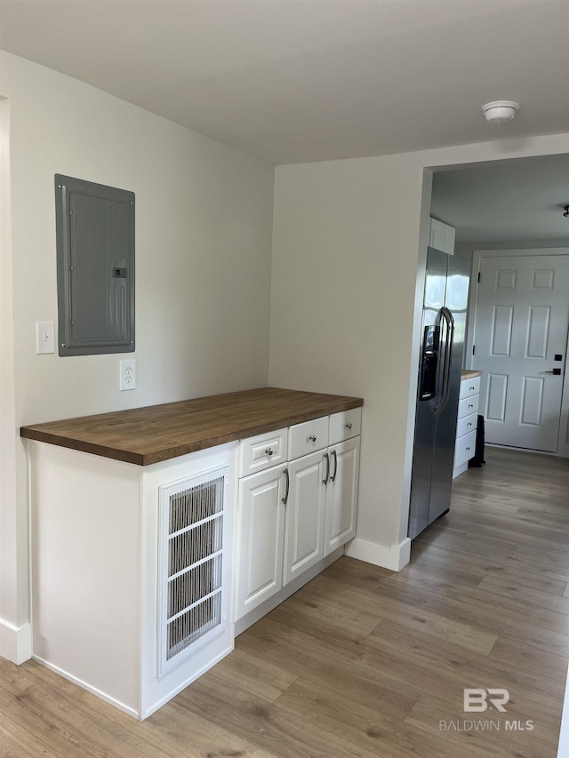 kitchen featuring stainless steel fridge, light wood-style flooring, electric panel, visible vents, and butcher block countertops