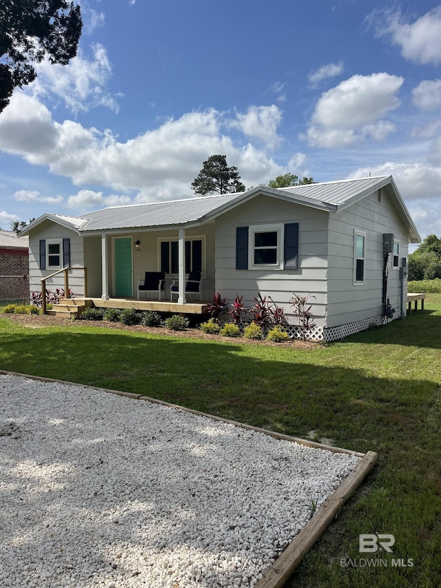 ranch-style house with metal roof, covered porch, and a front yard