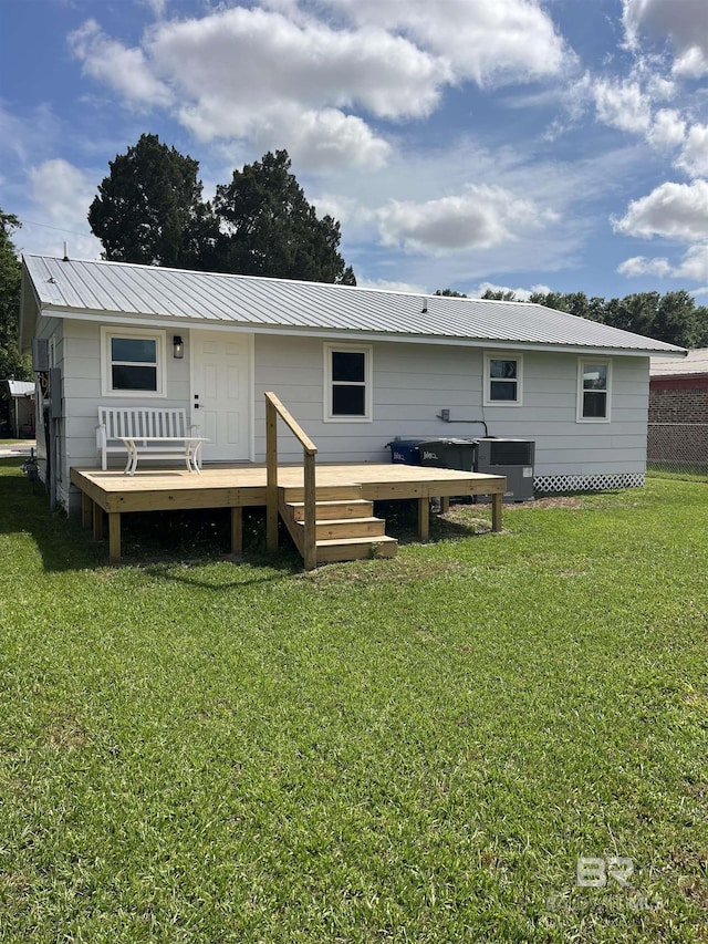 rear view of property with a yard, a deck, and metal roof