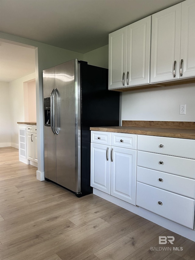 kitchen with stainless steel refrigerator with ice dispenser, light wood-style flooring, white cabinetry, baseboards, and dark countertops