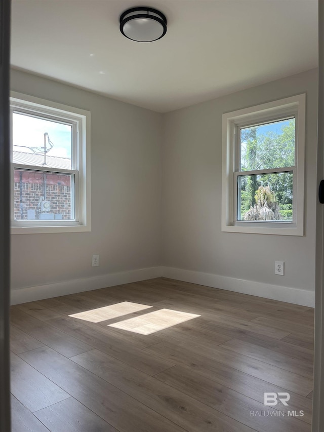 unfurnished room with baseboards and wood finished floors