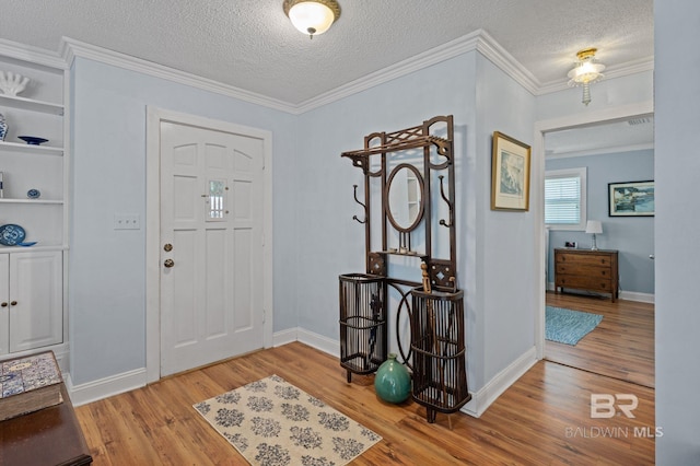 entryway with wood-type flooring, ornamental molding, and a textured ceiling