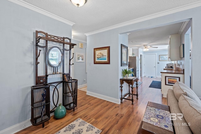 entrance foyer featuring wood-type flooring, a textured ceiling, ornamental molding, and ceiling fan