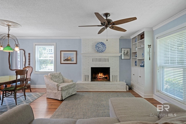 living room featuring a brick fireplace, ceiling fan, dark hardwood / wood-style floors, crown molding, and a textured ceiling