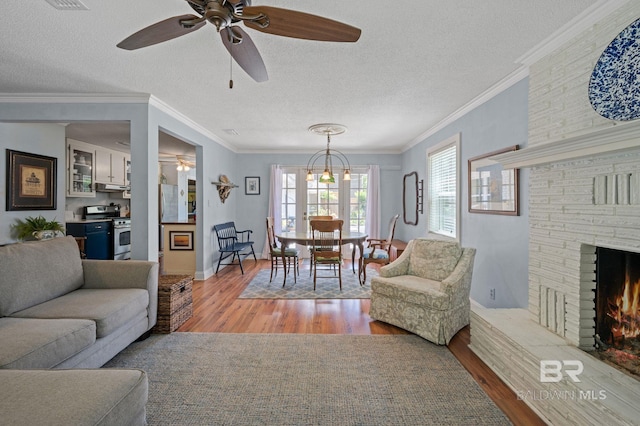 living room featuring a textured ceiling, light wood-type flooring, and ornamental molding