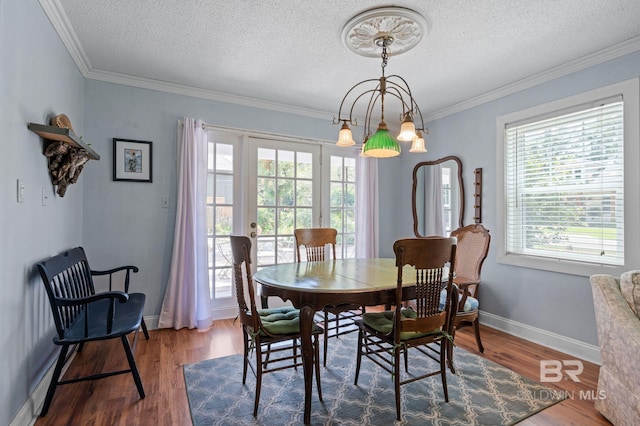 dining room with ornamental molding, dark wood-type flooring, an inviting chandelier, and a textured ceiling