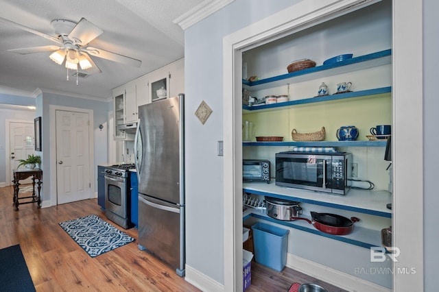 kitchen with white cabinets, ornamental molding, a textured ceiling, dark wood-type flooring, and appliances with stainless steel finishes