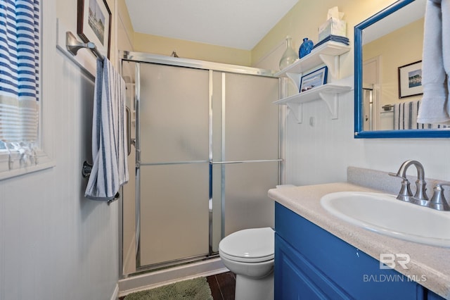 bathroom with toilet, vanity, and a shower with shower door