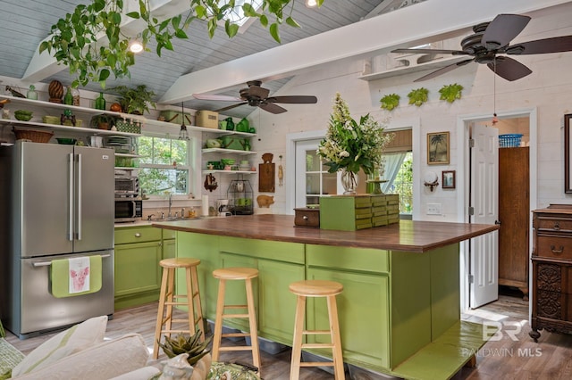 kitchen with butcher block countertops, appliances with stainless steel finishes, vaulted ceiling with beams, and a breakfast bar area