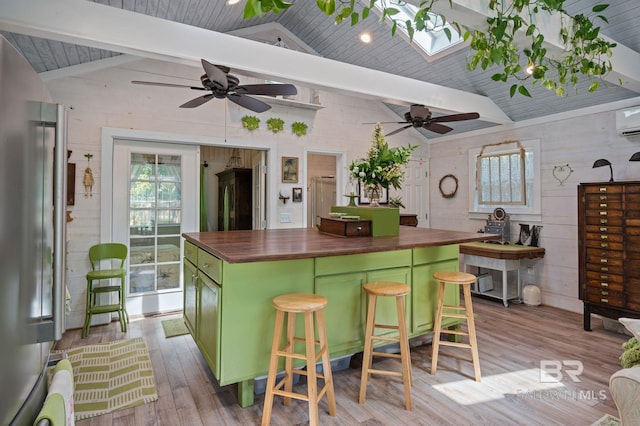 kitchen featuring green cabinetry, a center island, a breakfast bar, butcher block countertops, and vaulted ceiling with skylight