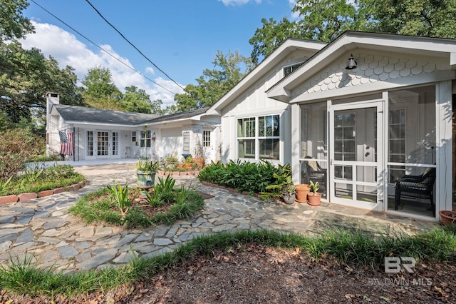 back of property featuring french doors, a sunroom, and a patio