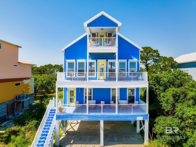 rear view of property with a carport, stairway, and a balcony