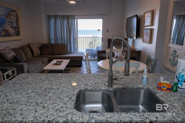 interior space featuring tile patterned flooring, light stone counters, and sink