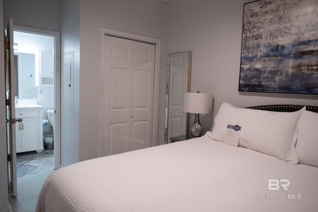 bedroom featuring a closet, light tile patterned floors, and connected bathroom