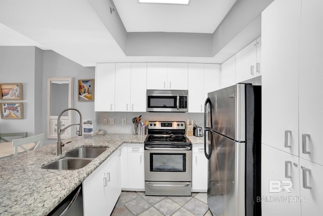 kitchen featuring white cabinets, light stone counters, stainless steel appliances, and sink