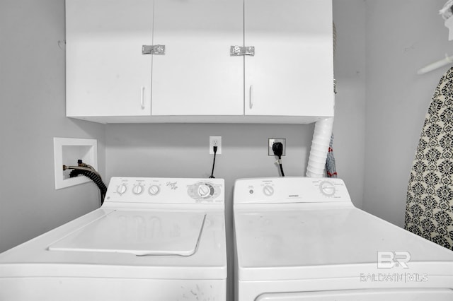 clothes washing area with separate washer and dryer and cabinets