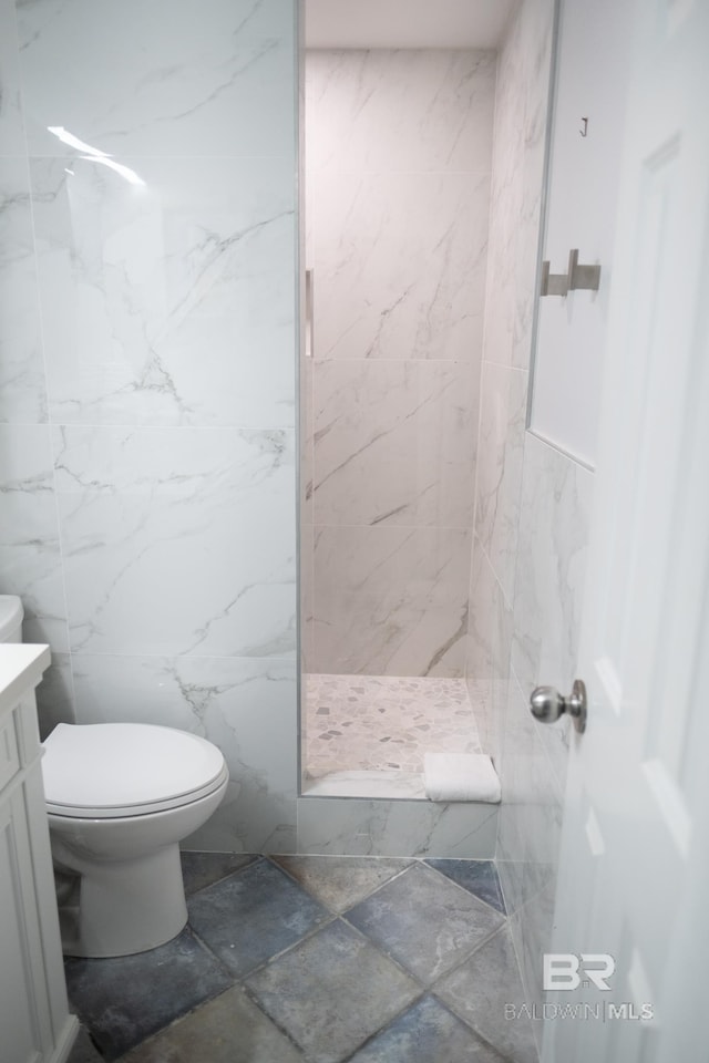 bathroom featuring vanity, toilet, tile walls, and tiled shower