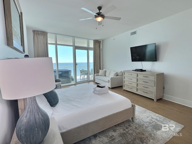 bedroom featuring visible vents, access to outside, expansive windows, wood finished floors, and baseboards