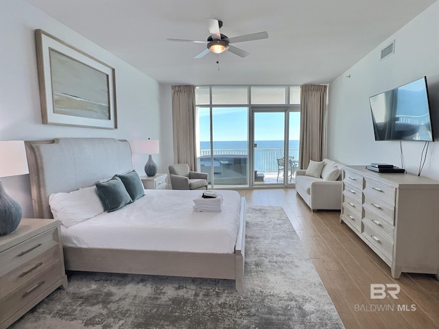 bedroom with access to exterior, visible vents, floor to ceiling windows, wood finished floors, and a ceiling fan