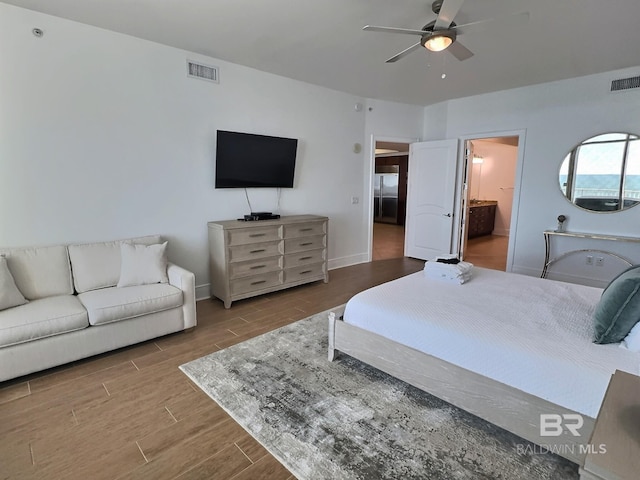 bedroom with baseboards, visible vents, ensuite bath, and wood finish floors