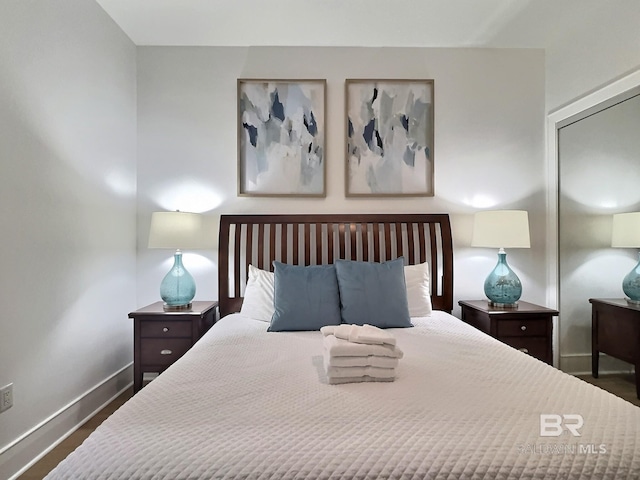 bedroom with dark wood finished floors, baseboards, and a closet