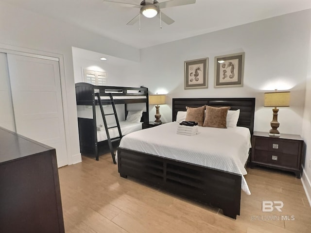 bedroom with a closet, light wood-style flooring, a ceiling fan, and baseboards