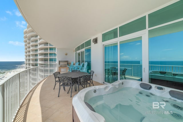 balcony featuring a water view, outdoor dining space, and a hot tub