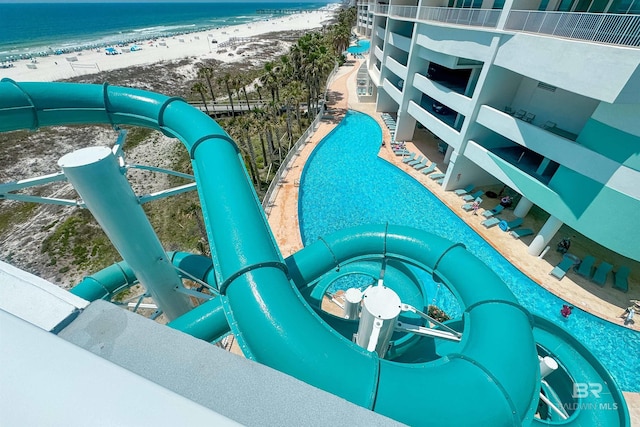 view of swimming pool with a beach view and a water view