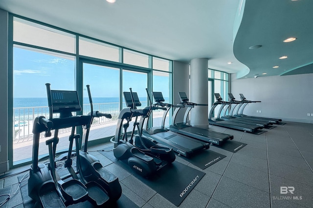 exercise room with recessed lighting, a water view, baseboards, and expansive windows