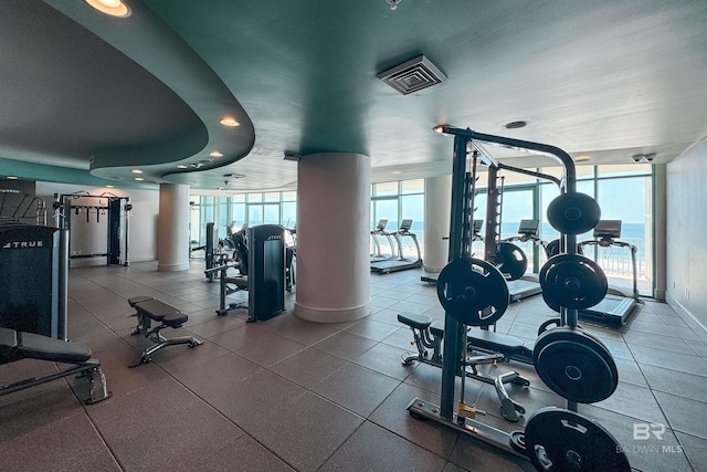 gym with a wall of windows, baseboards, and ornate columns