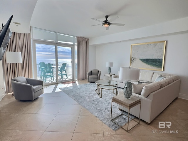 tiled living area with floor to ceiling windows and ceiling fan