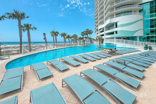 pool featuring a water view, fence, and a patio area