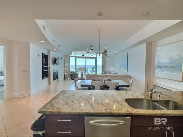 kitchen featuring open floor plan, dishwasher, light tile patterned flooring, a glass covered fireplace, and a sink