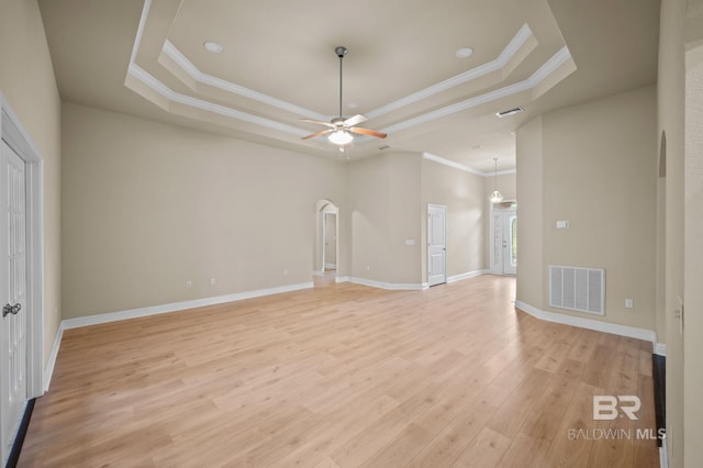 750 Cheswick Ave, Fairhope, AL 36532 - unfurnished living room featuring a raised ceiling, arched walkways, a ceiling fan, light wood-style floors, and crown molding